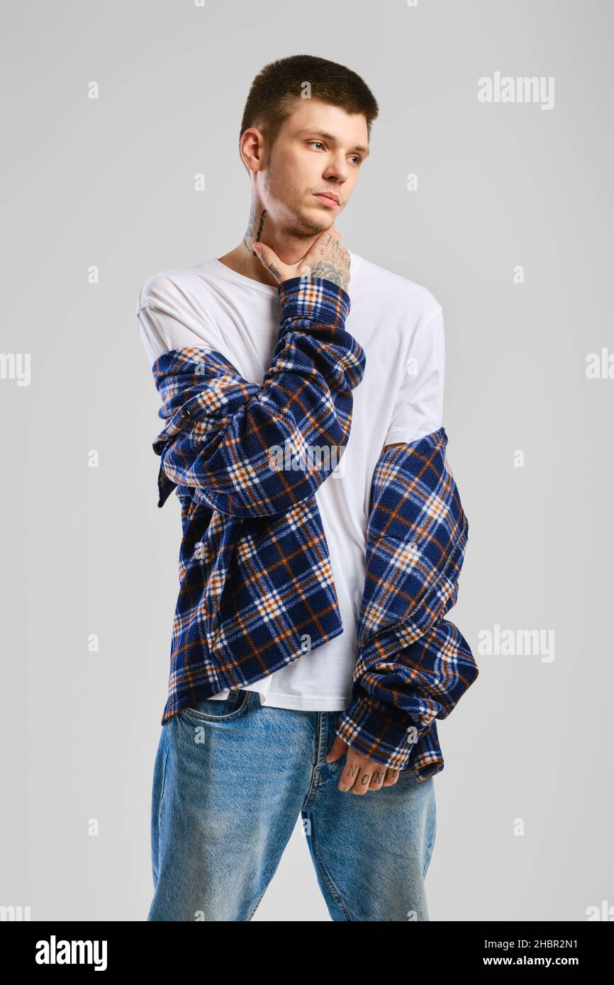 Young cocky man in checkered shirt and jeans touching his throat Stock Photo