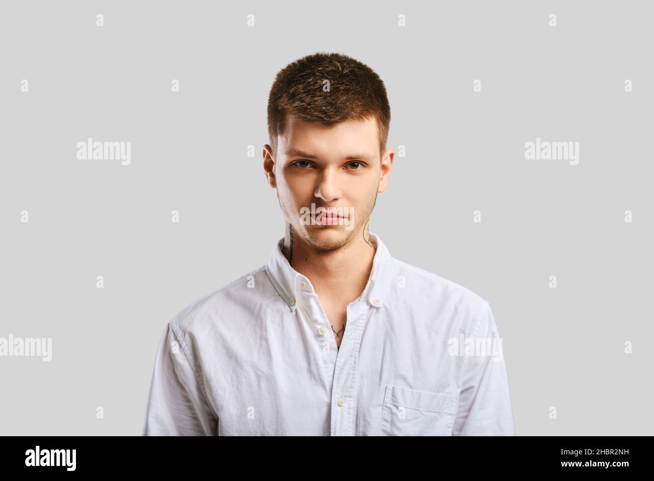 Young handsome man in white shirt posing over grey background Stock Photo