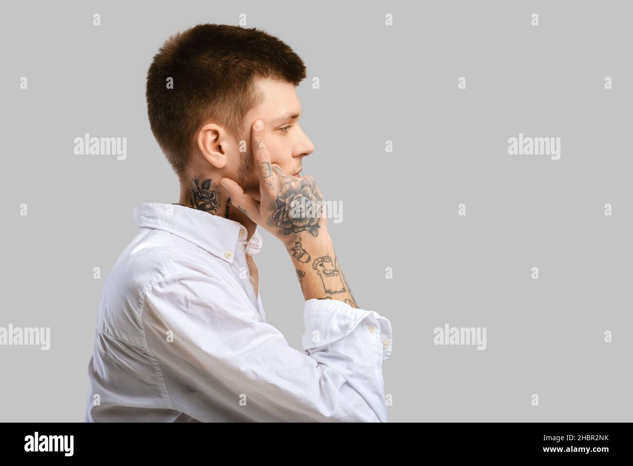 Young man touching his temple with a finger, standing in profile Stock Photo