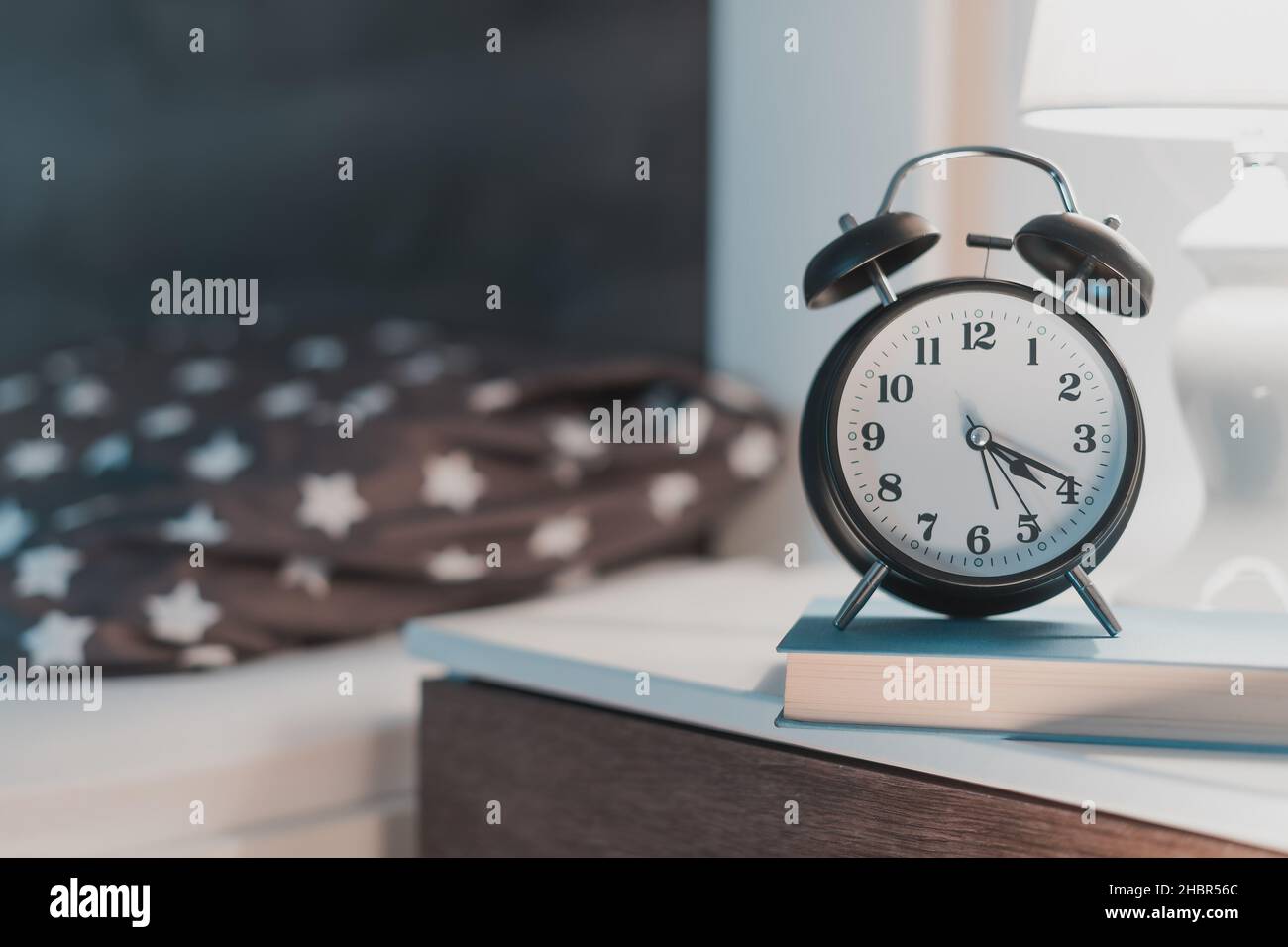 Bedroom bedside lamp and clock at 4 o'clock in the morning for insomnia and sleeplessness concept, low light ambient Stock Photo