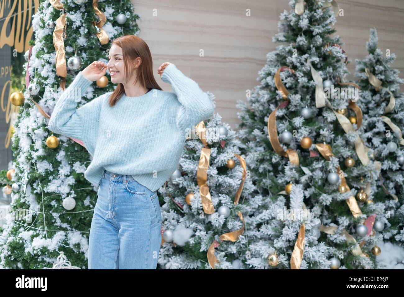 https://c8.alamy.com/comp/2HBR6J7/new-year-portrait-of-beautiful-smiling-caucasian-young-woman-in-cozy-wool-warm-light-blue-sweater-standing-near-decorated-christmas-tree-happy-person-2HBR6J7.jpg