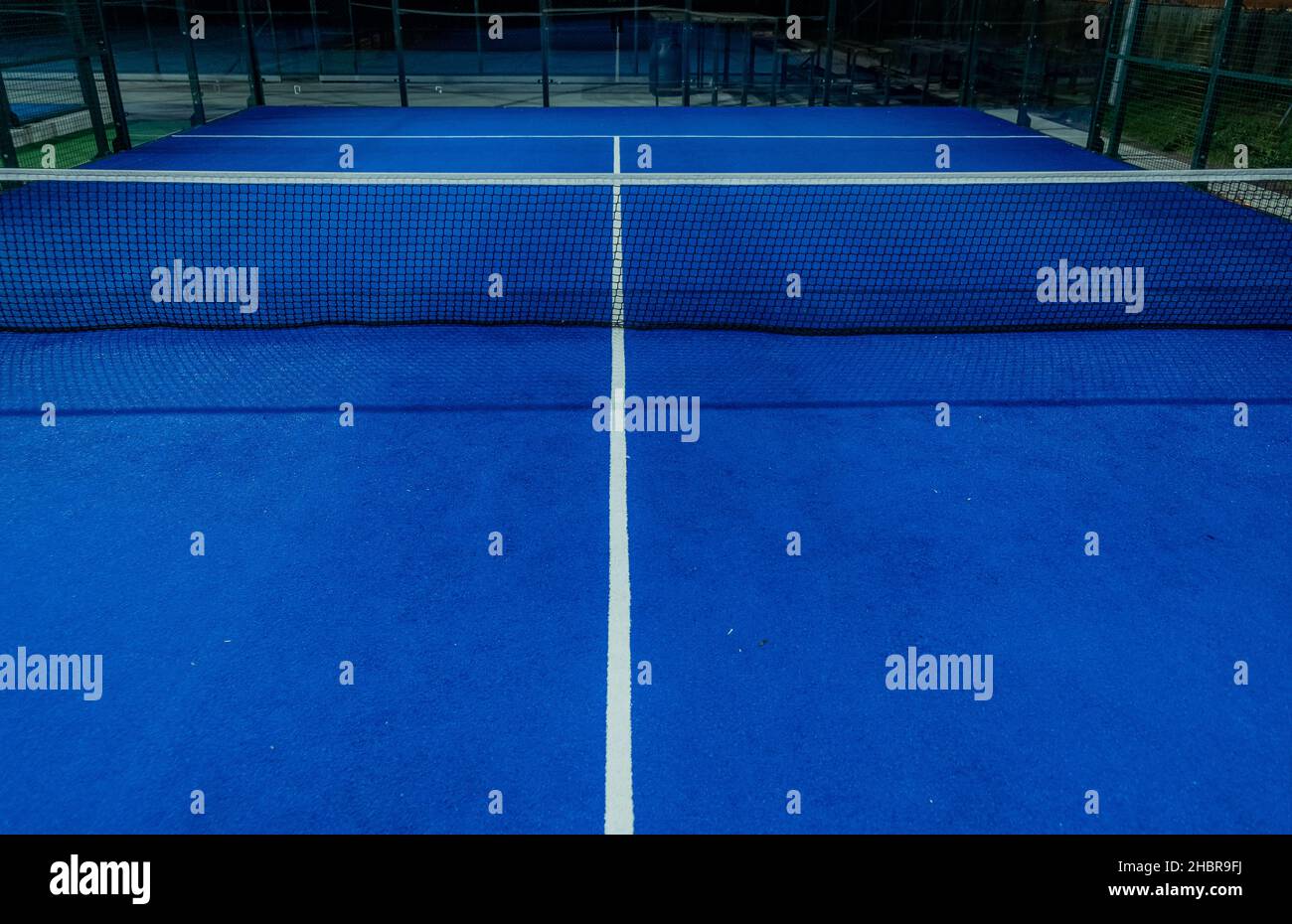 Blue paddle tennis court at night. Racket sports concept, healthy sports. Stock Photo