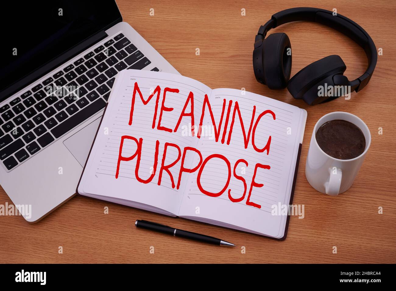 Hand writing sign Meaning Purpose. Word Written on The reason for which something is done or created and exists Blank Notepad Laptop With Pen And Stock Photo