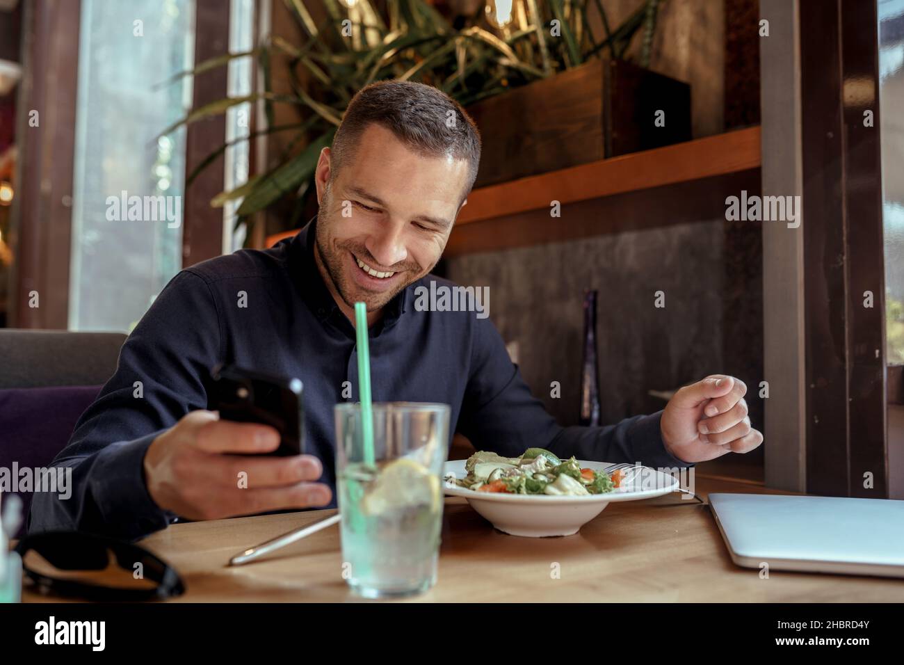 Businessman is using his phone while having lunch in restaurant Stock Photo