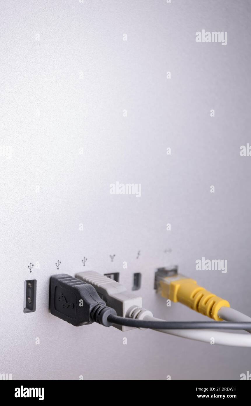 USB, Thunderbolt and Ethernet cables connected to ports on the back of an Apple Thunderbolt Display, close-up view Stock Photo