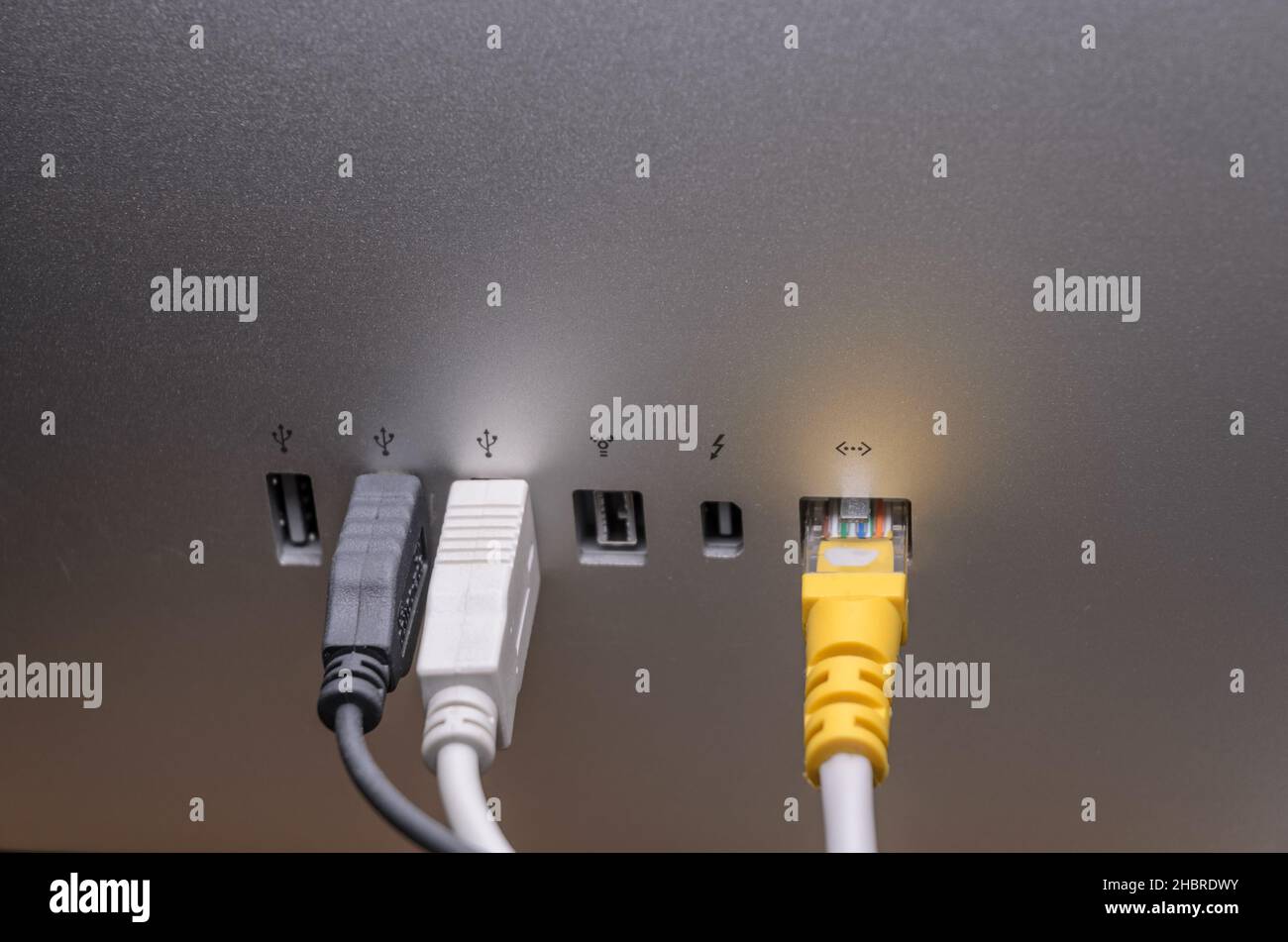 USB, Thunderbolt and Ethernet cables connected to ports on the back of an Apple Thunderbolt Display, close-up view Stock Photo
