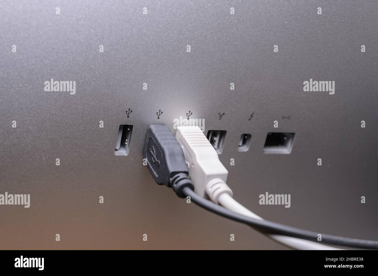 USB cables connected to ports on the back of an Apple Thunderbolt Display Stock Photo