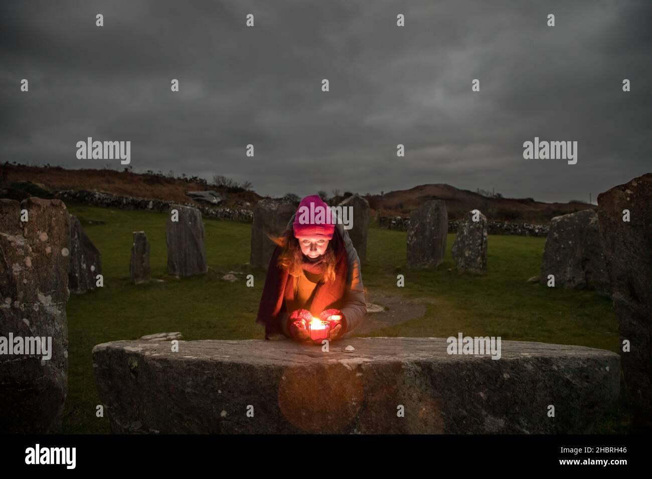 Drombeg, Glandore, Cork, Ireland. 21st December 2021.Shaman and healer Amy Russell from Rosscarbery lighting a candle on the Altar Stone while  waiting to observe the Sunrise during the Winter solstice at Drombeg Stone Circle outside Glandore, County Cork, Ireland. - Credit; David Creedon / Alamy Live News Stock Photo