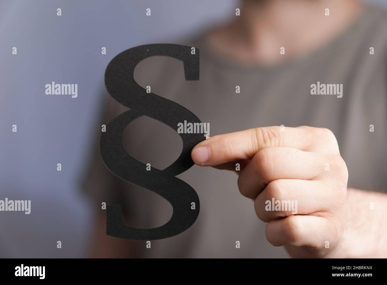 A male hand holding a black paragraph law sign Stock Photo - Alamy