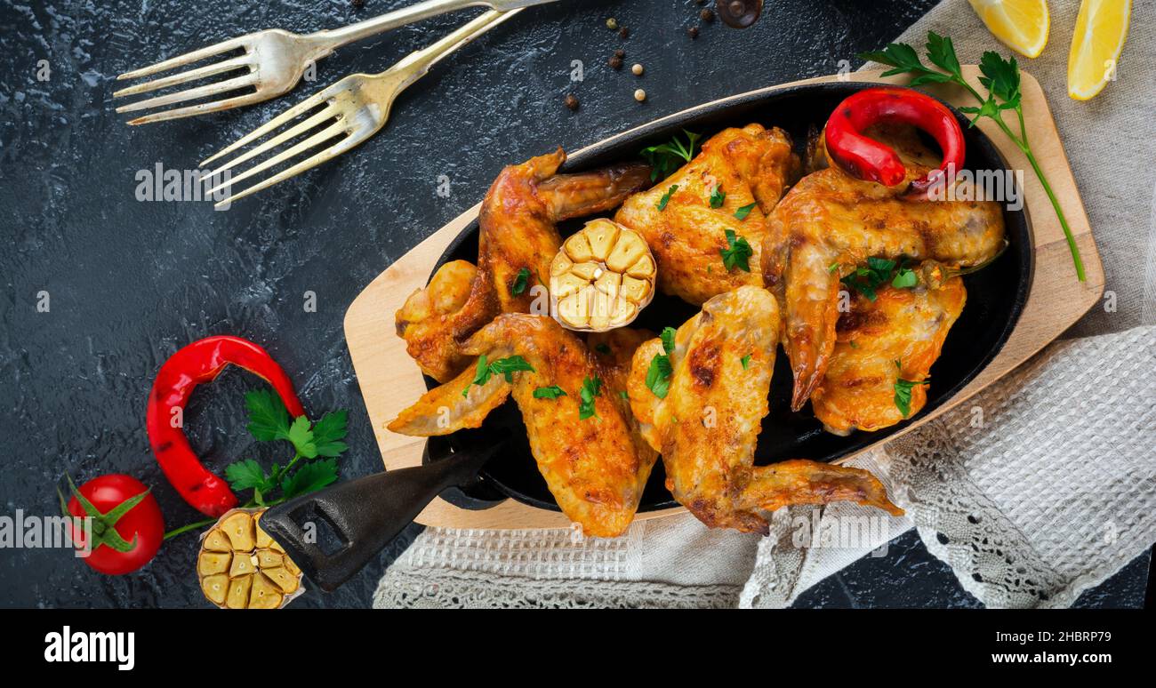 Grilled chicken wings on a cast iron pan on a black oval stone