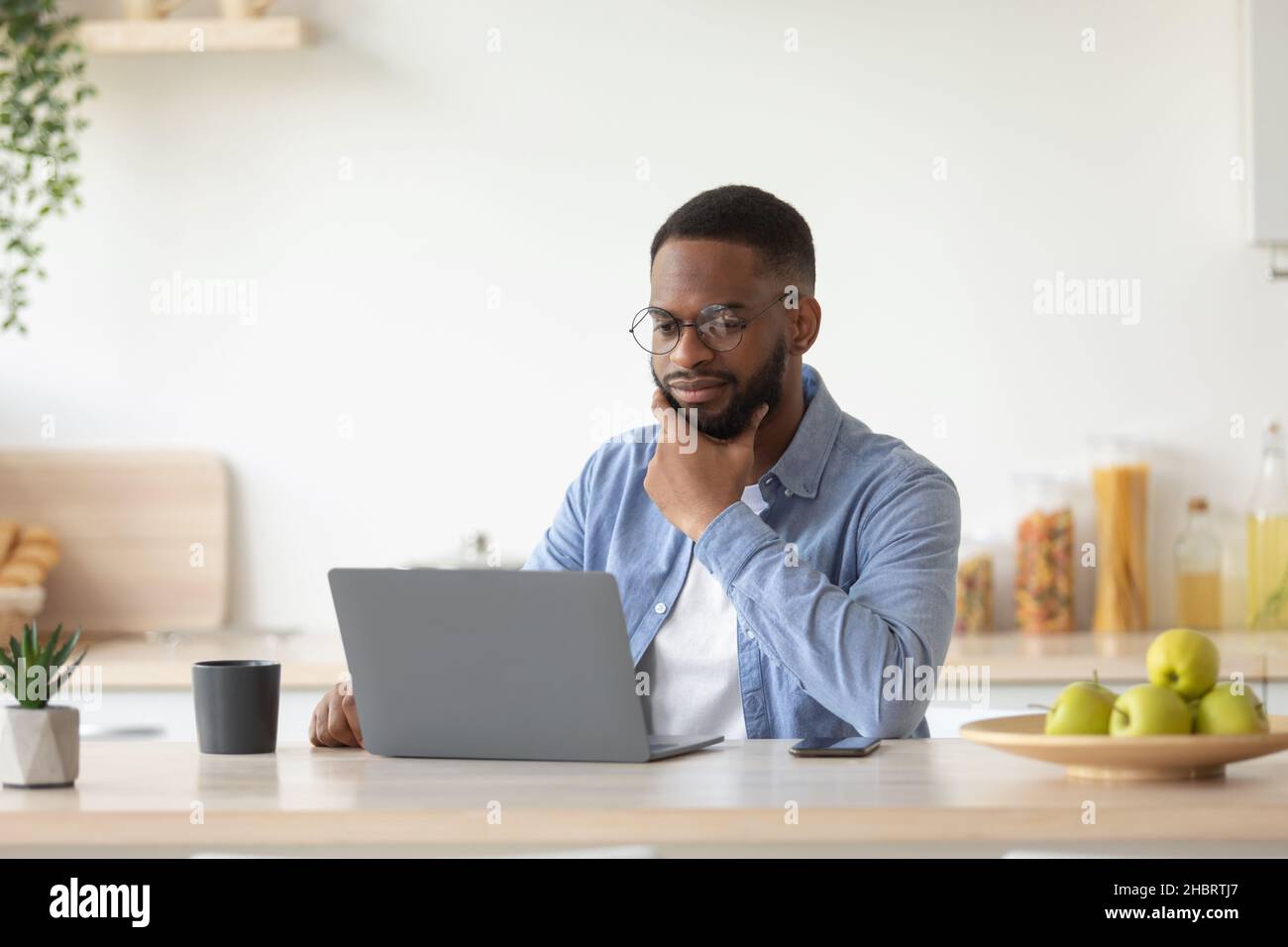 Serious millennial african american bearded businessman in glasses works at laptop and ponders problem solution Stock Photo