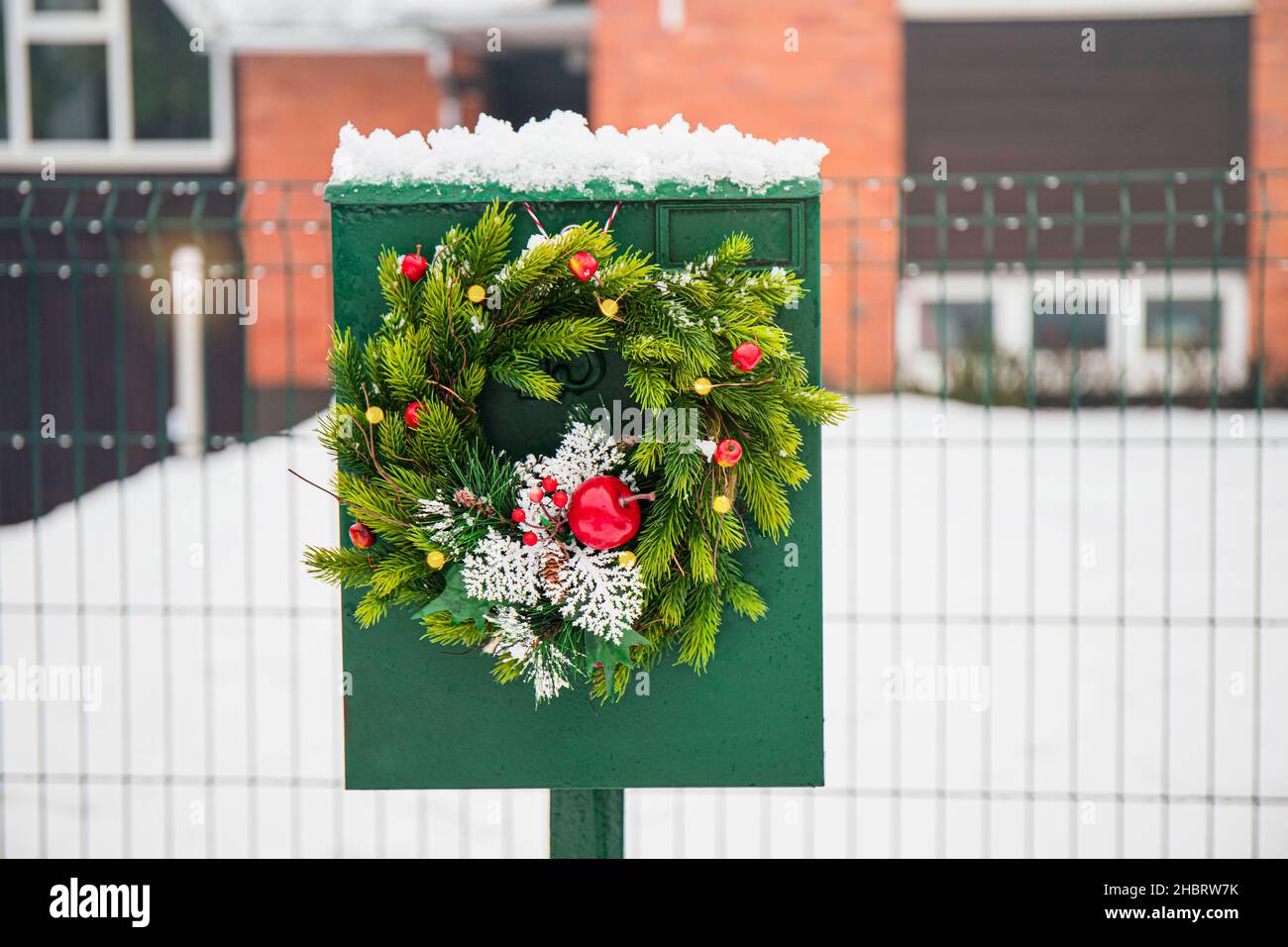 Domestic mail box decorated with spruce tree Christmas wreath outdoors in snowy winter day. Holiday moods. Stock Photo