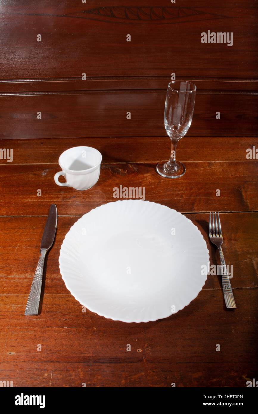 empty plate spoon fork and knife on table Stock Photo