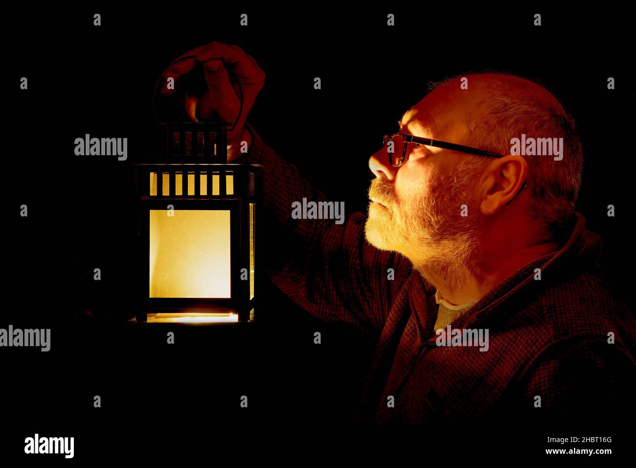 Grey haired man holding a lantern. low key lighting Stock Photo