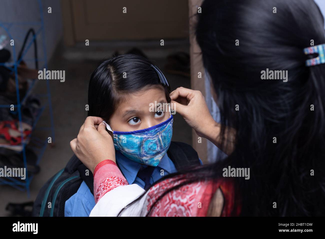 An Indian mother preparing her girl child with nose mask protection to send to school after pandemic Stock Photo