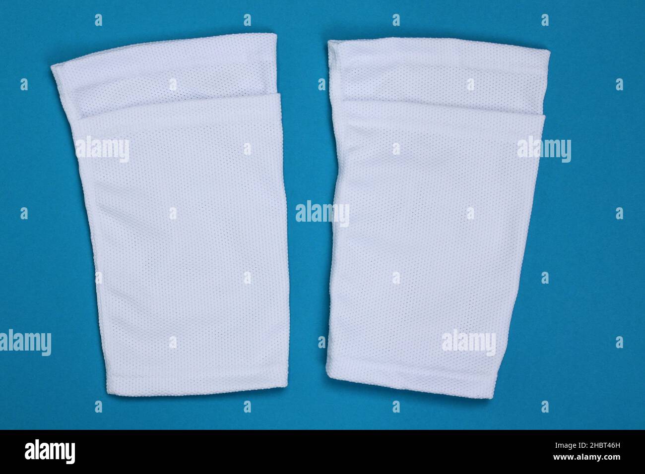 Football shin guards in white fabric. Shin sleeves made of polyester on a light blue background. White shield holders. Football ammunition for athlete Stock Photo