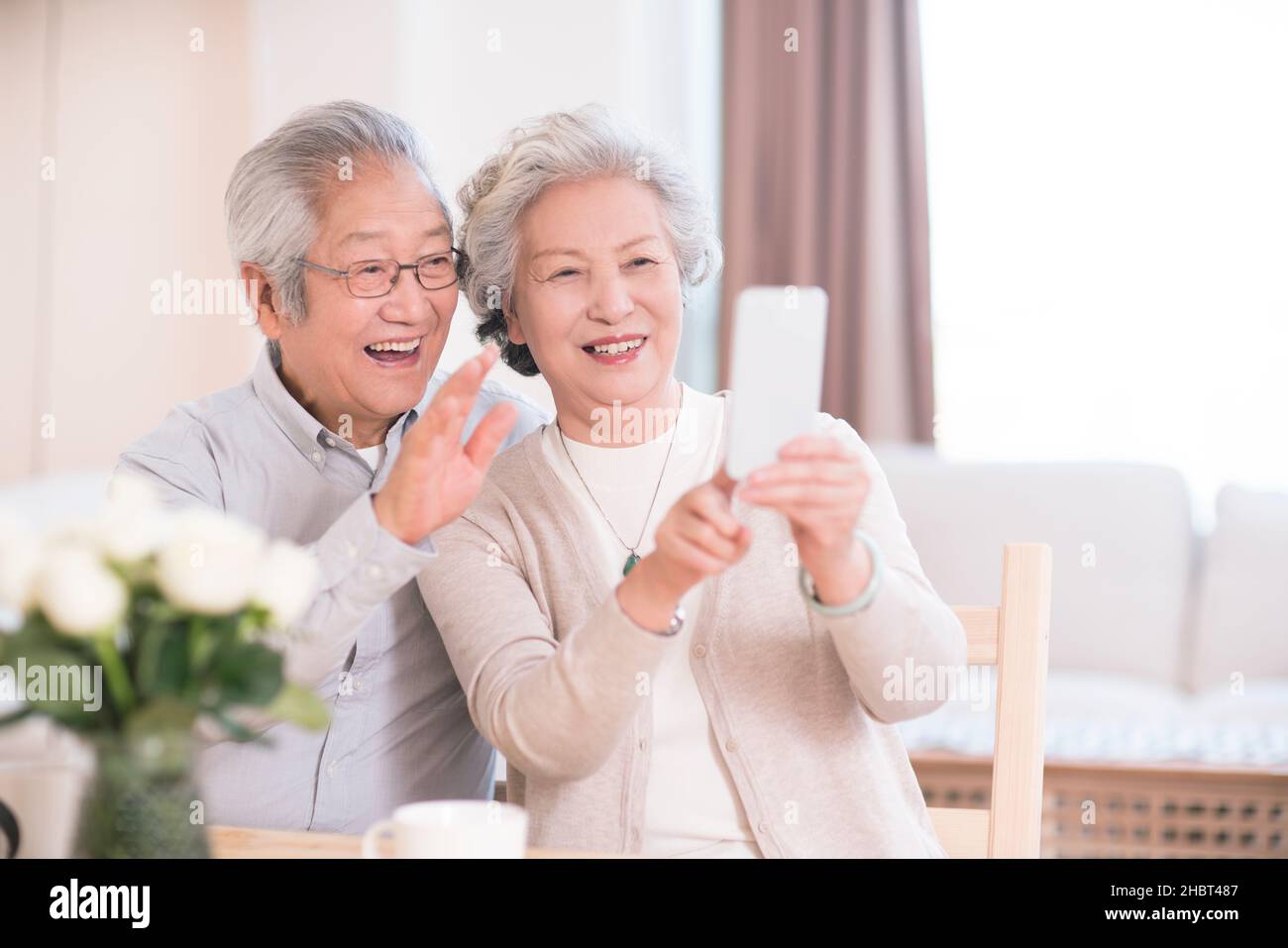Elderly couple using a mobile phone to take selfies at home Stock Photo
