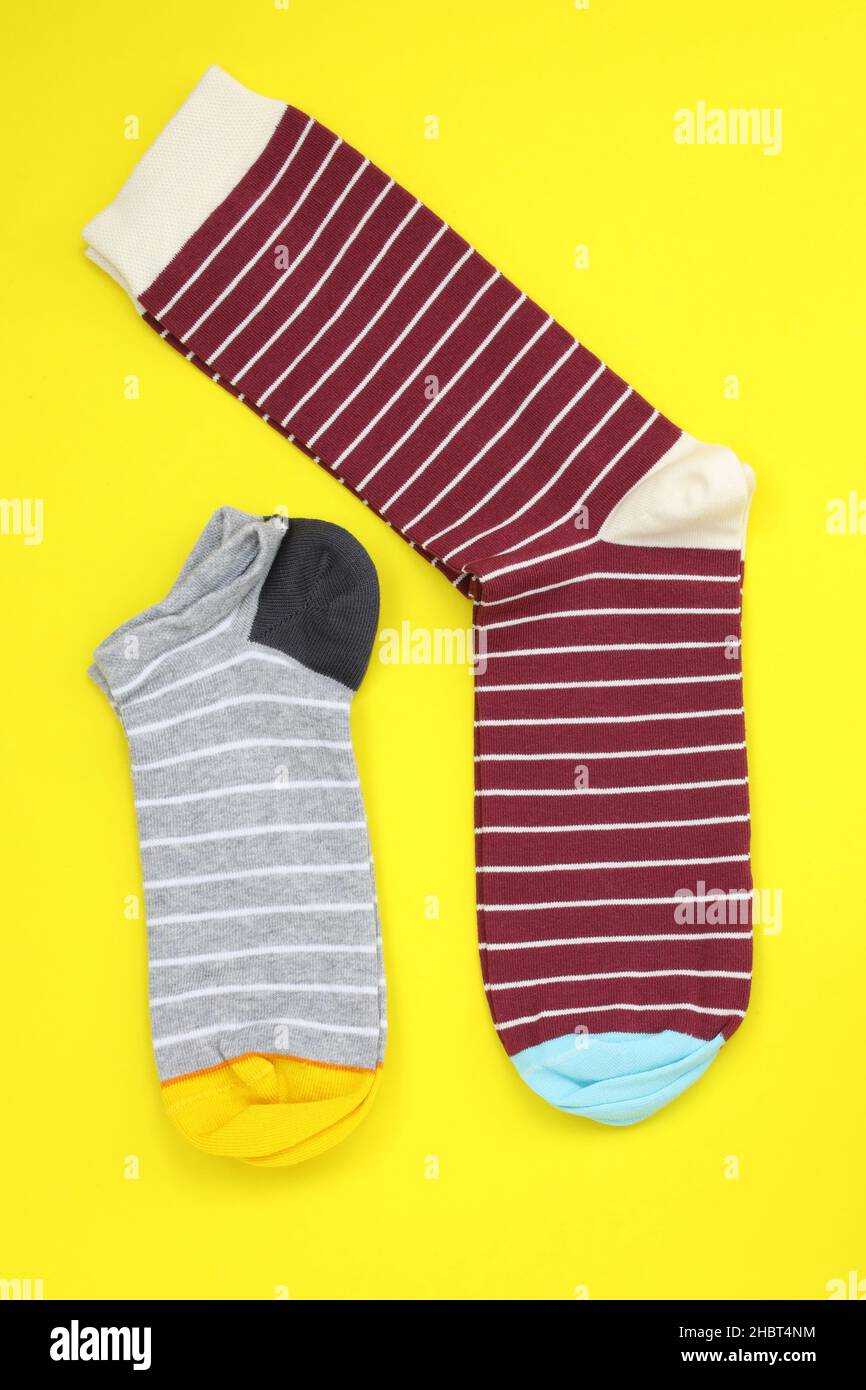 Short striped toe and long striped toe top view. Bright socks of different sizes on a yellow background. Colored socks for sports. Stock Photo