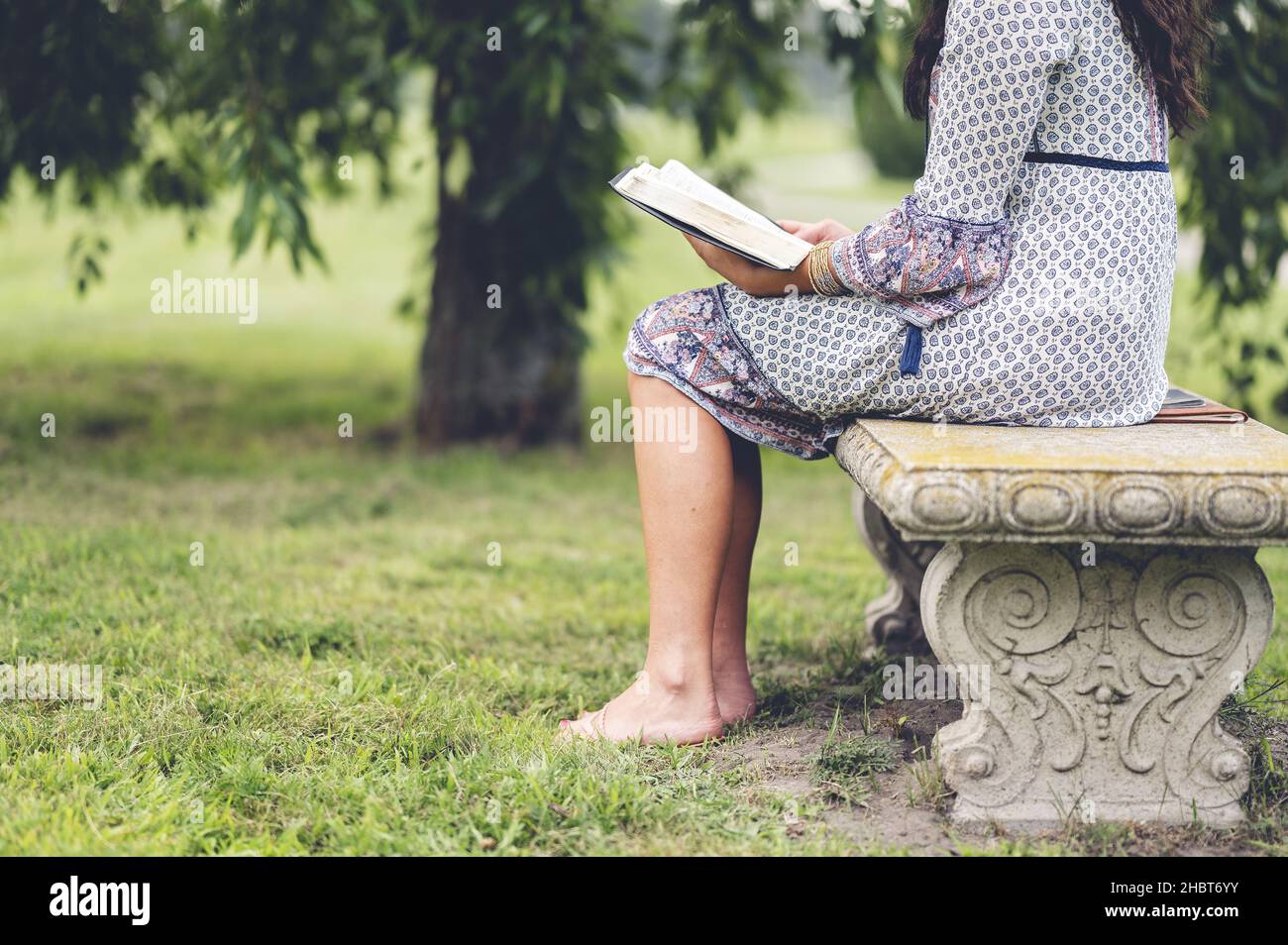 A detail of a lonely female sitting on a park bench with a book Stock ...