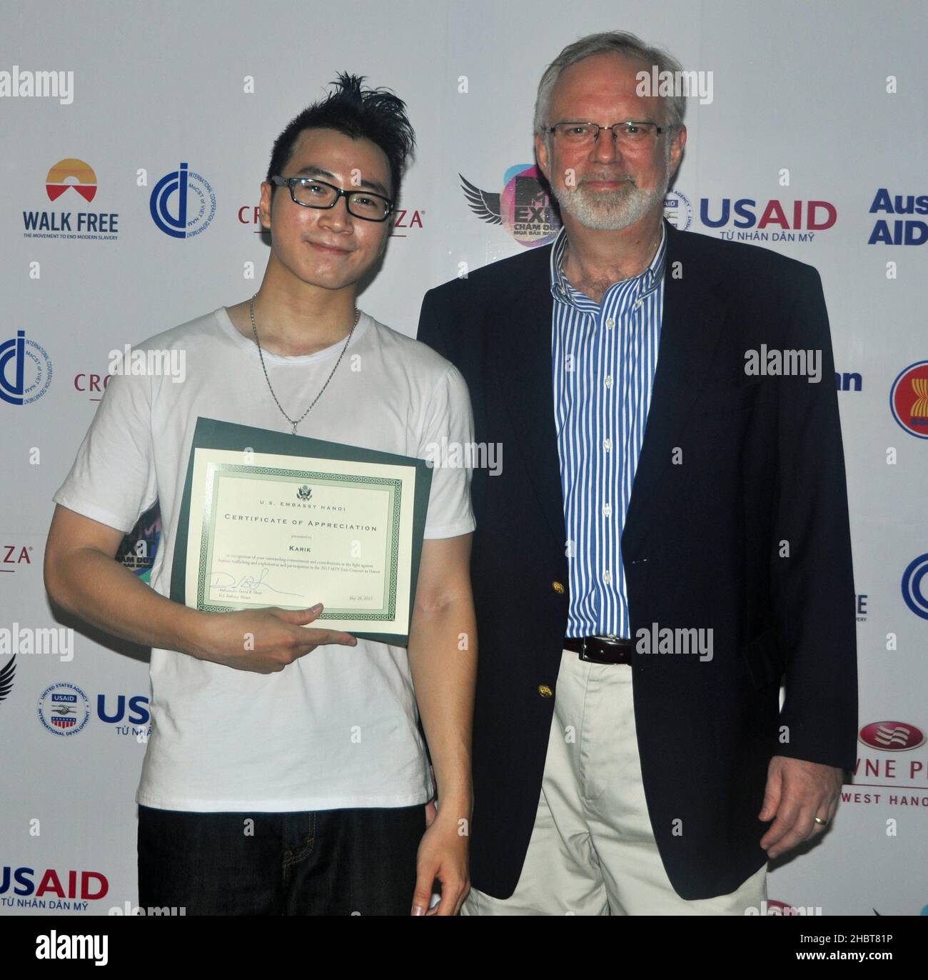 2010s Vietnam:  U.S. Ambassador David Shear presents Vietnamese rapper, Karik, with a certificate of appreciation for taking parting in the MTV EXIT concert against human trafficking and exploitation ca.  26 May 2012 Stock Photo