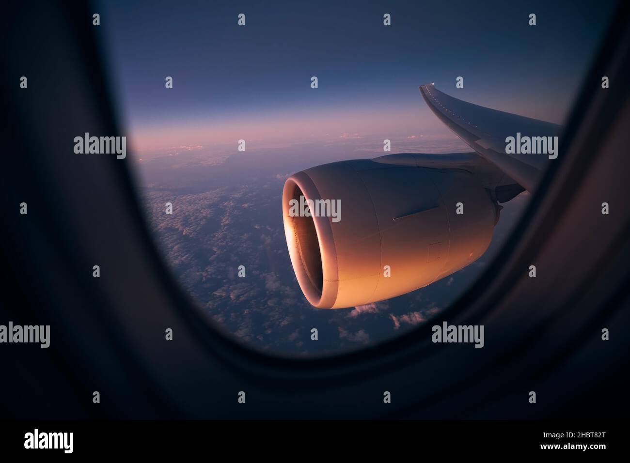 View from window of airplane during night flight above ocean. Selective focus on jet engine. Stock Photo
