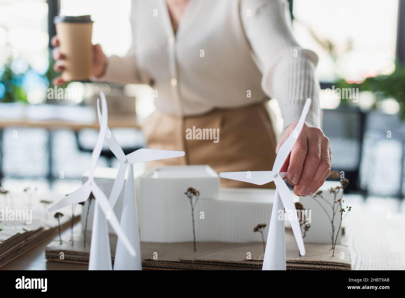 Cropped view of blurred businesswoman with paper cup touching model of ...