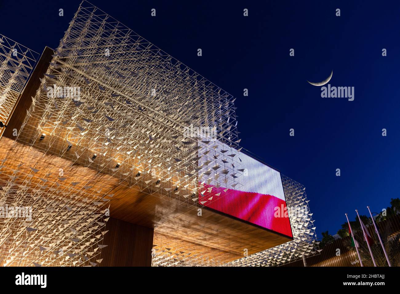 Dubai, UAE, 09.12.2021. Illuminated Poland Pavilion at Expo 2020 Dubai, wooden facade covered in sculptures of flying birds, dark night sky with cresc Stock Photo
