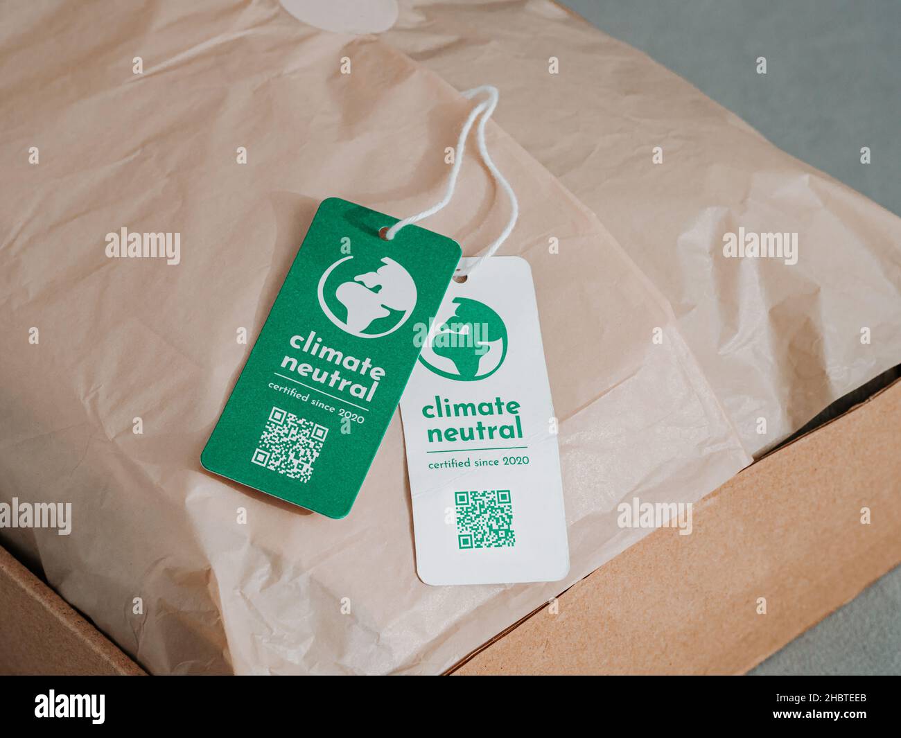 Carbon neutral product in craft corrugated box with label Climate neutral. Carbon neutral label concept in apparel, fashion, logistics indusrty and ethical consumption. Increasing awareness for customers about carbon footpint Stock Photo