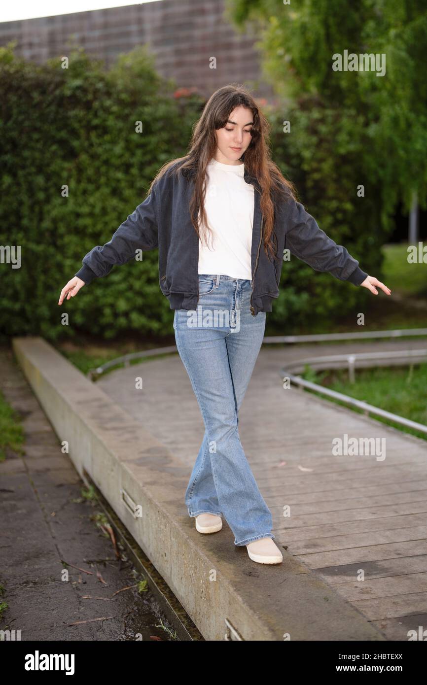 Teenage Woman Balancing on the Edge of a Walkway Stock Photo