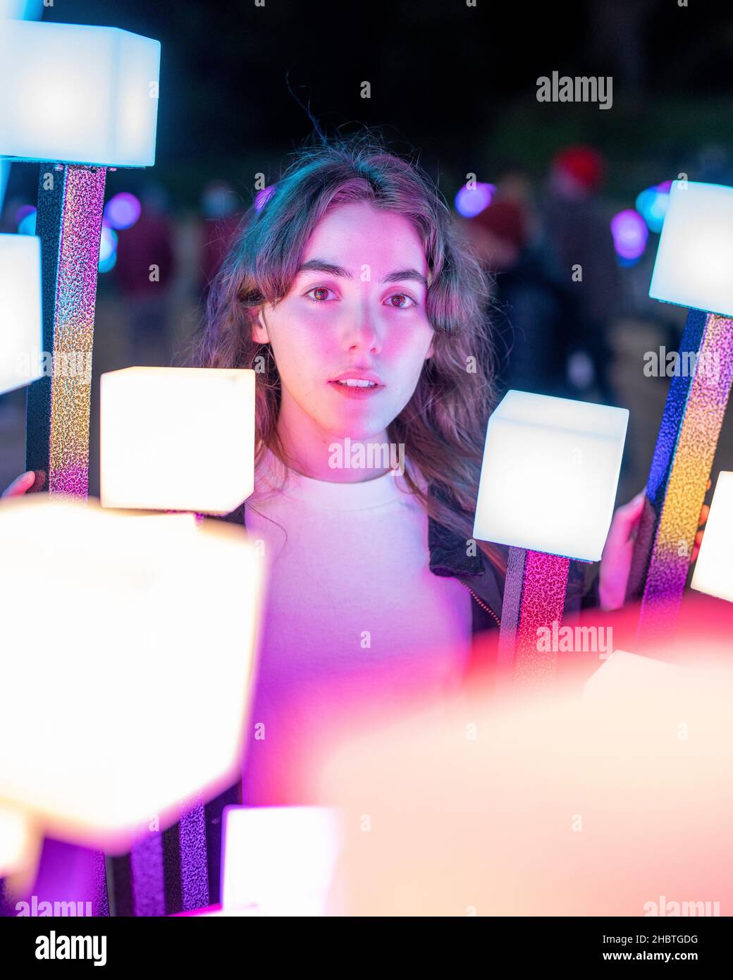 Teenage Woman Surrounded by Artistic Holiday Lights Stock Photo
