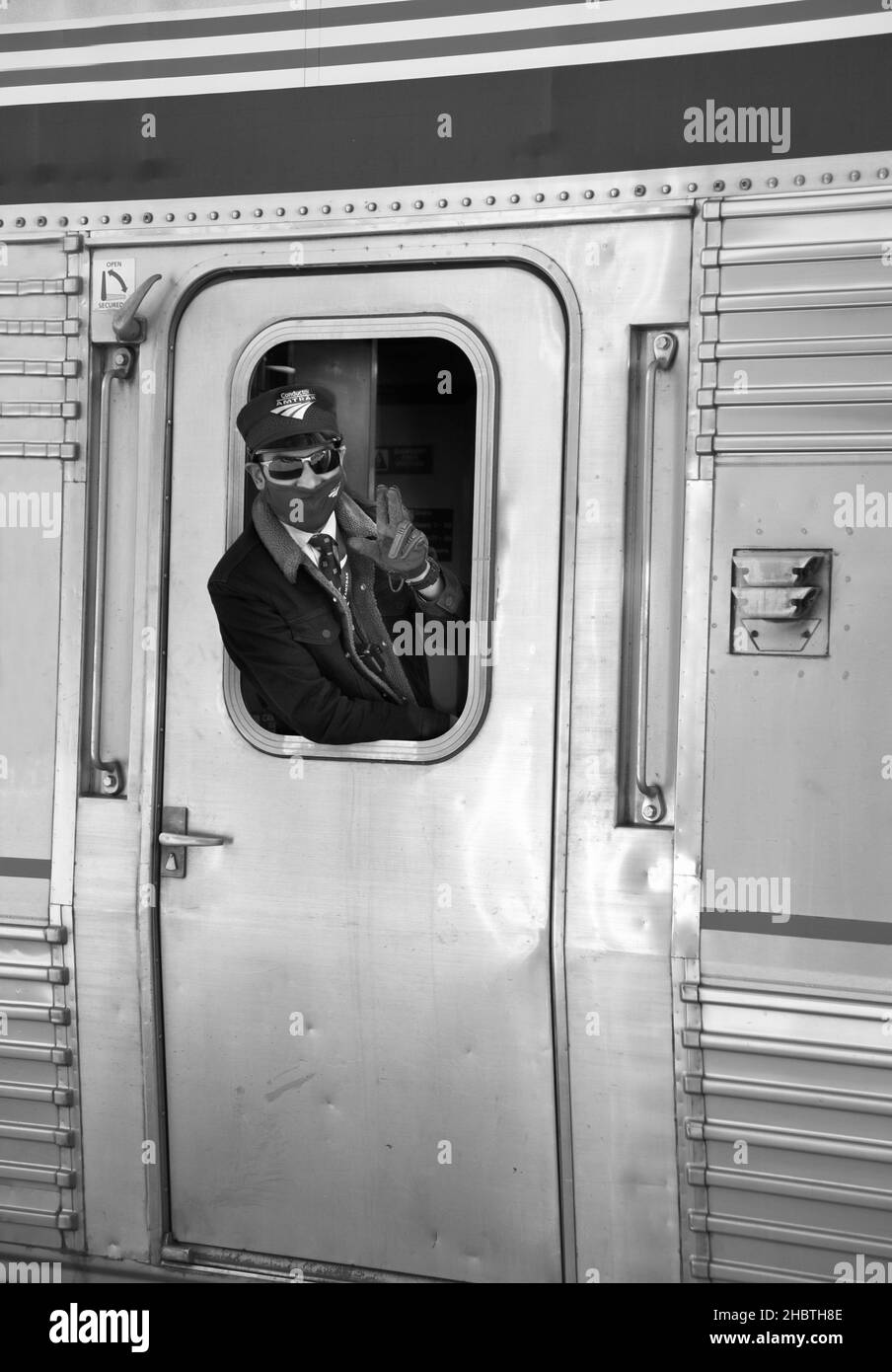 An Amtrak conductor waves as the passenger train departs from the station in Lamy, New Mexico, with service between Chicago and Los Angeles. Stock Photo