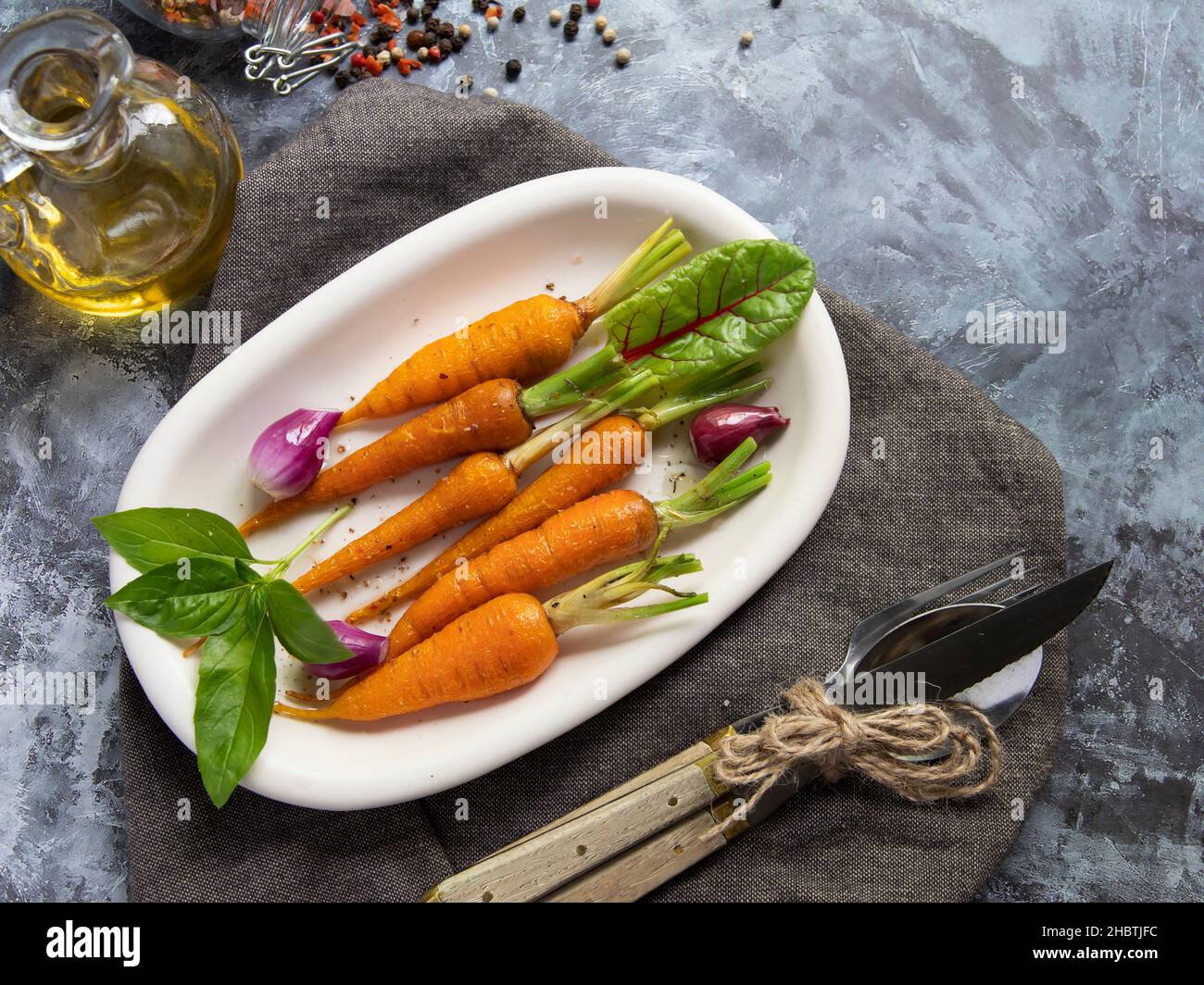 baked roast baby carrots in a plate, basil and spices vegan dish. Top view Stock Photo