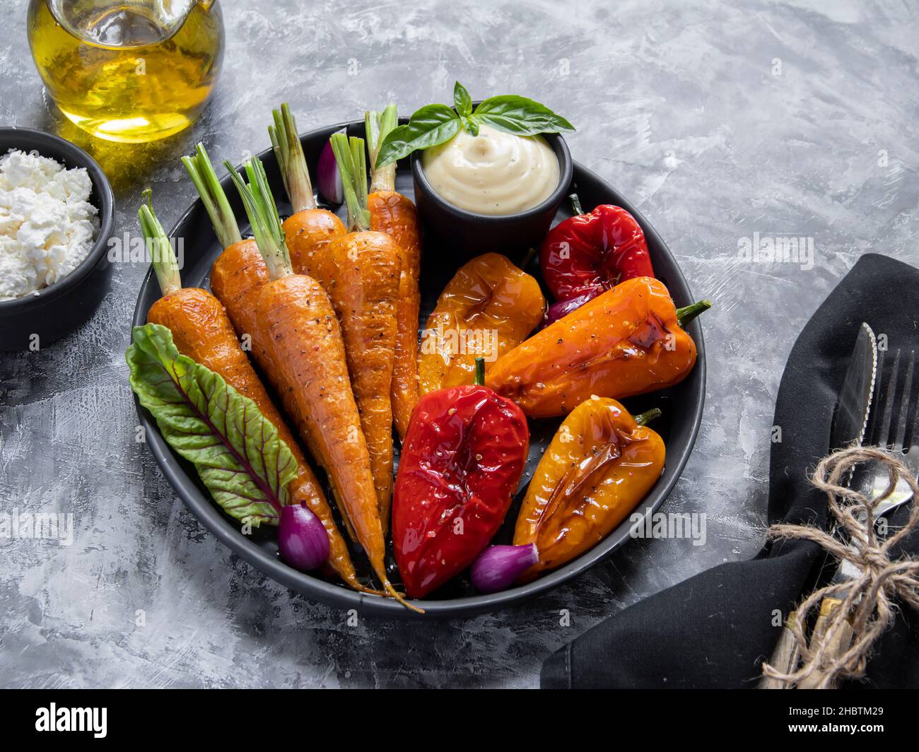 baked roast baby carrots, bell pepper in a plate, basil vegan dish goat cheese Stock Photo
