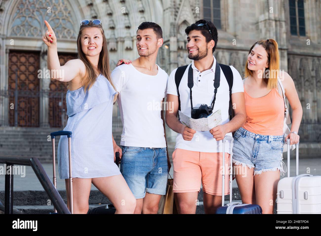 Four cheerful traveling young people with map Stock Photo