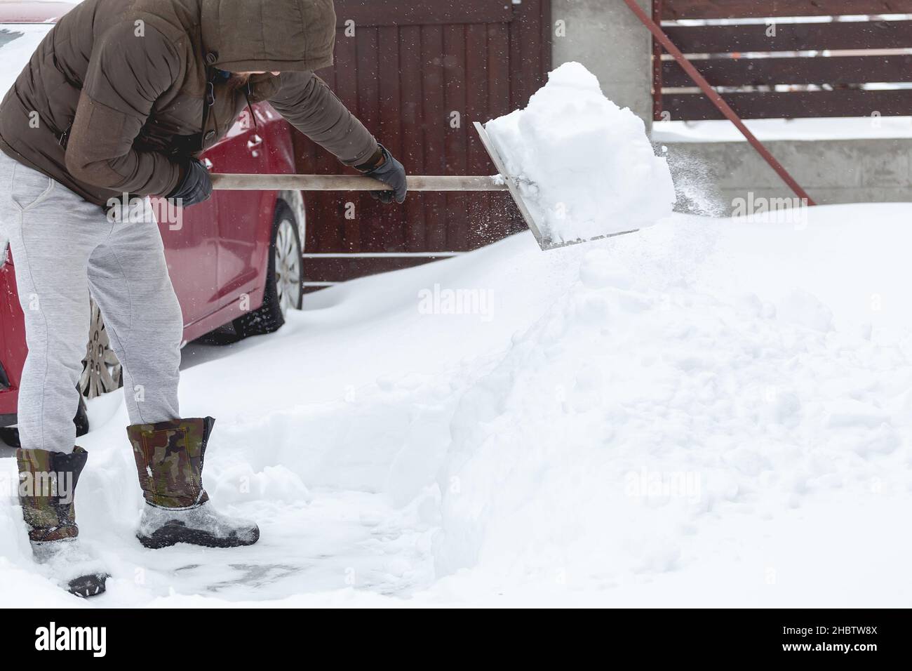 man cleaning snow with a shovel in hands near his car Stock Photo