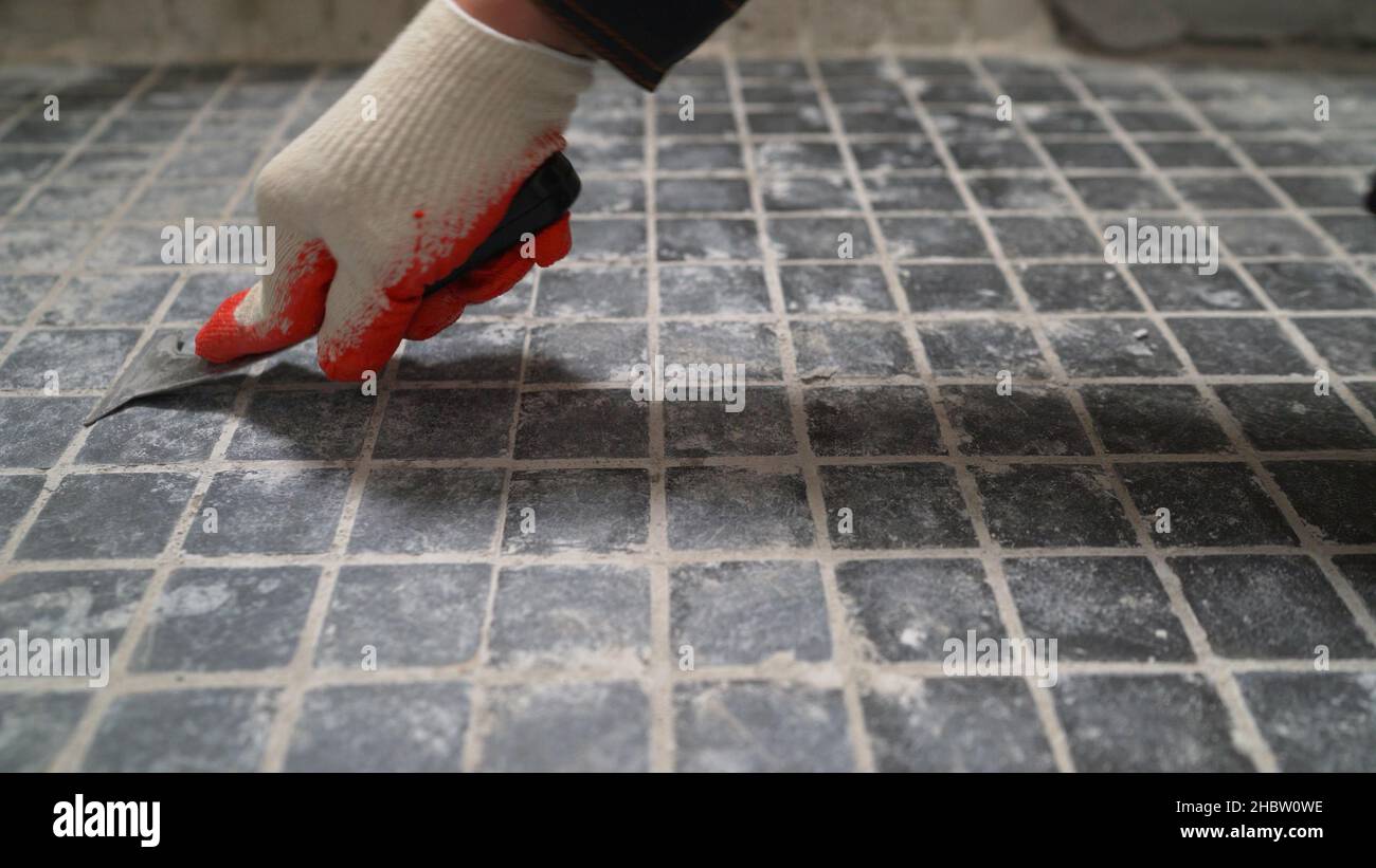 Sanding old floor tiles with a trowel. Cleaning old floor tiles Stock
