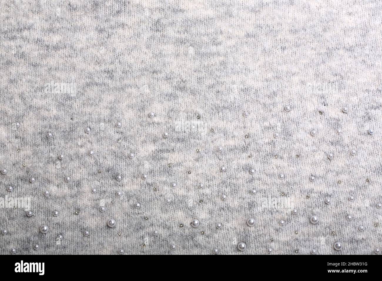 Knitted background. Light gray gentle wool background pattern. Background embroidered with beads Stock Photo