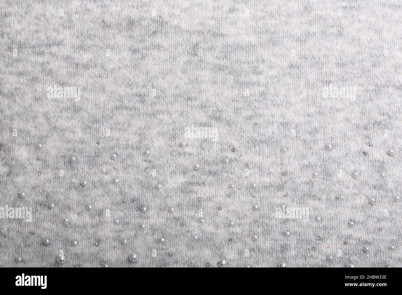 Knitted background. Light gray gentle wool background pattern. Background embroidered with beads Stock Photo