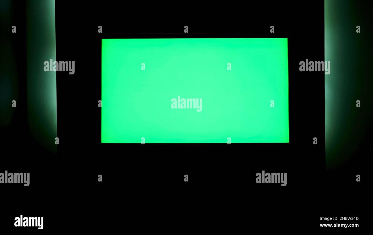 TV with horizontal green screen on a black wall with green illumination
