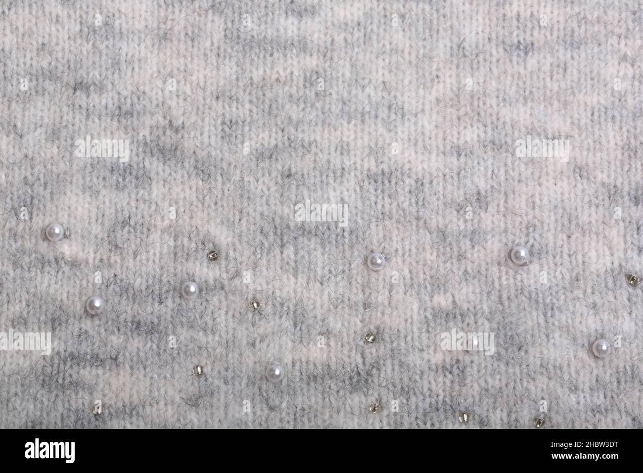 Knitted background. Light gray gentle wool background pattern. Background embroidered with beads Stock Photo
