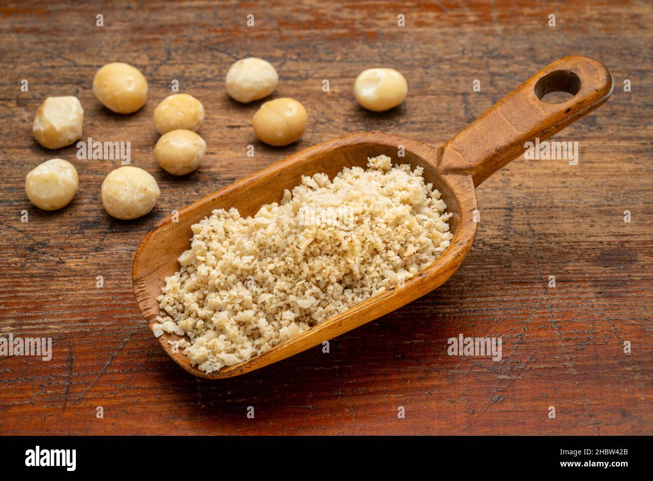 macadamia nut flour in wooden scoop on a rustic weathered wood, gluten