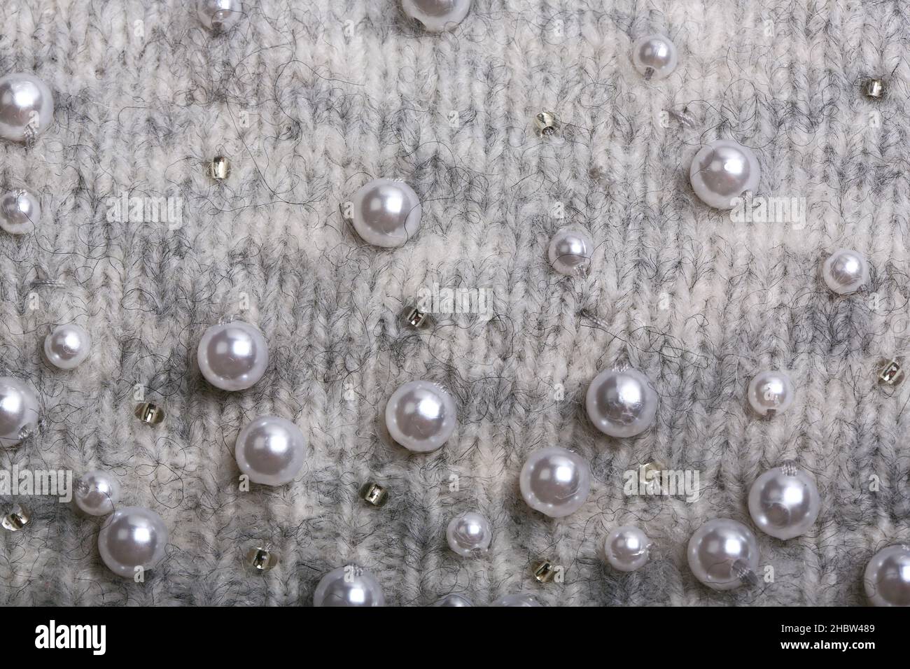 Knitted background. Light gray gentle wool background pattern. Background embroidered with beads Stock Photo