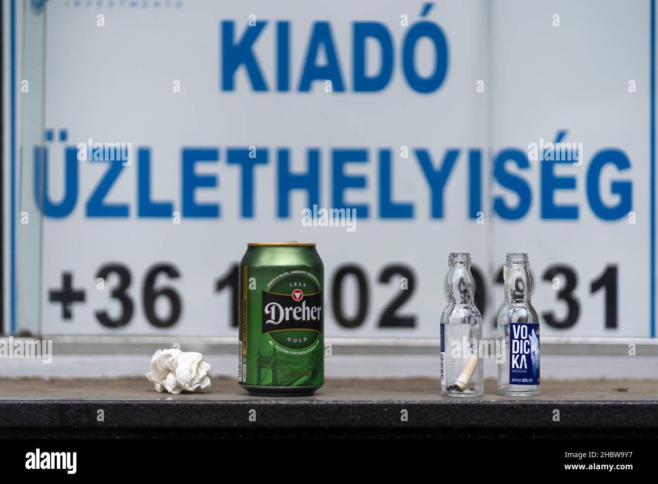 Empty beer can, small alcohol bottles, used tissue in front of shop window that is for sale. Sad reality during Covid time. Stock Photo