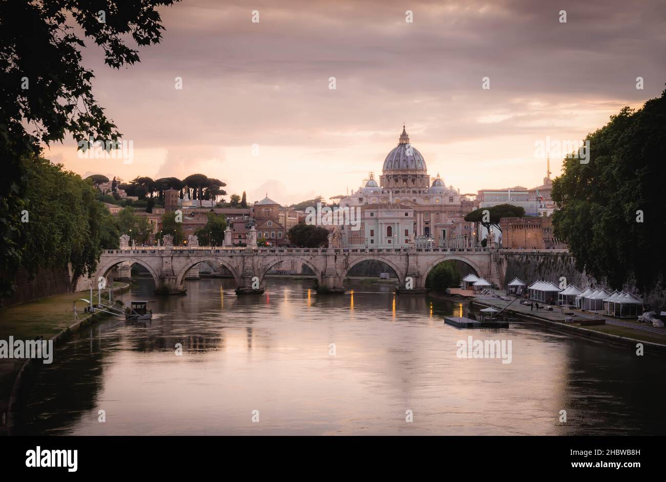 Tourist and Postcard View of St Angelo Bridge with Vatican and St Peters Basilica under Sunset Sky in Rome, Italy Stock Photo