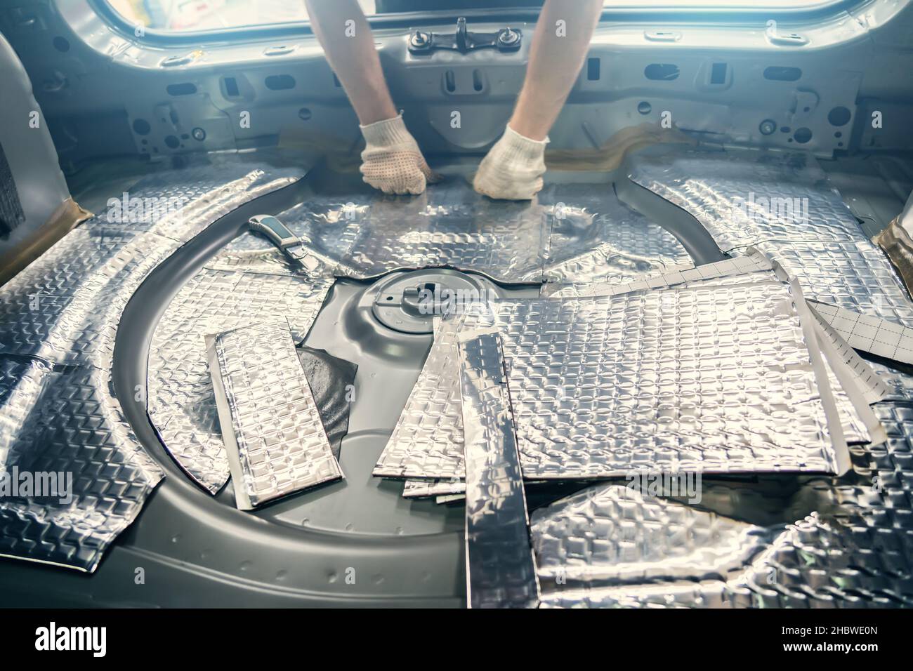 Auto service worker installs soundproofing material inside car interior, soundproofing