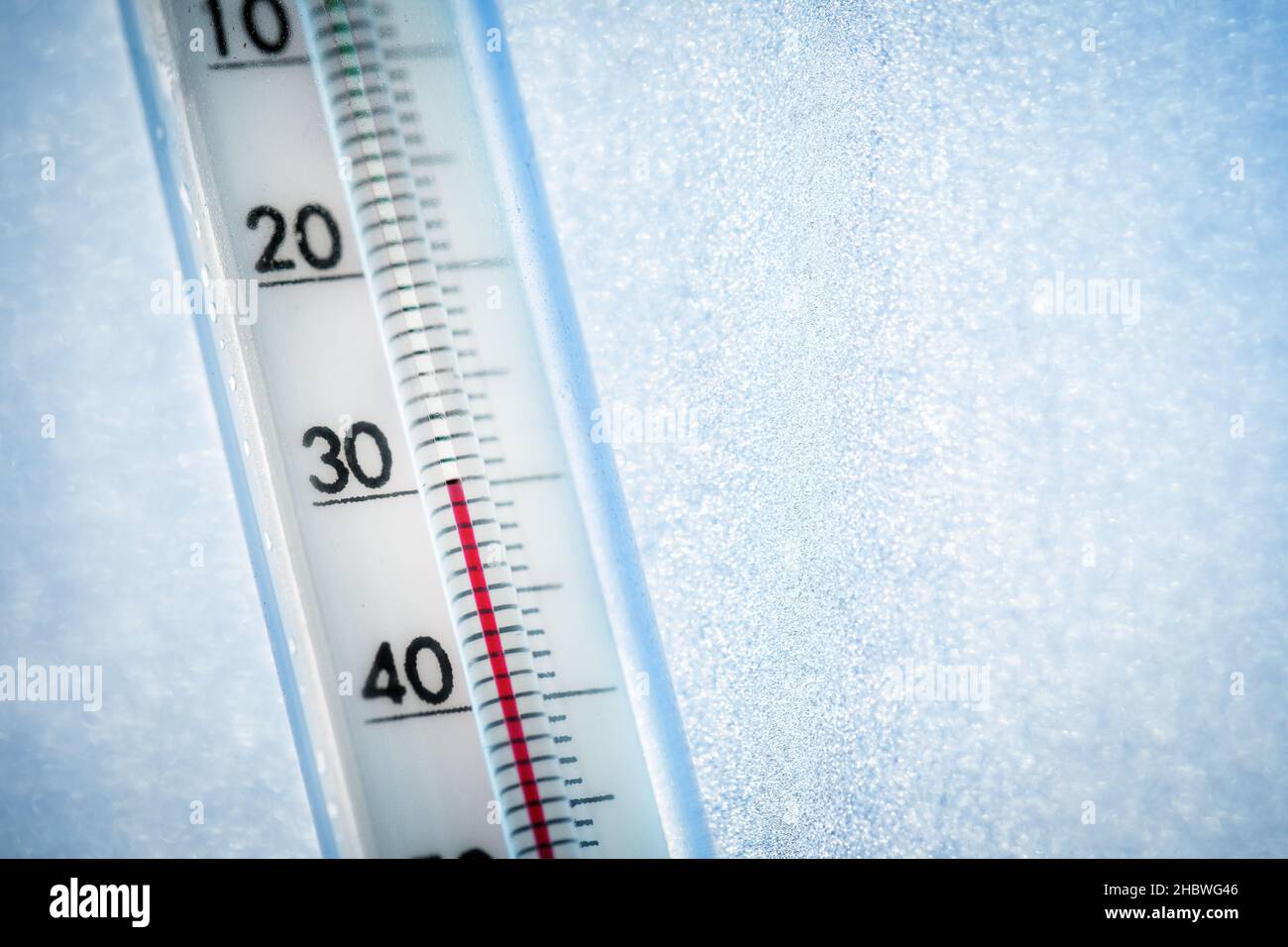 The thermometer shows a low temperature of minus 30 Celsius. Weather forecast. A frosty day and ice patterns on the glass Stock Photo