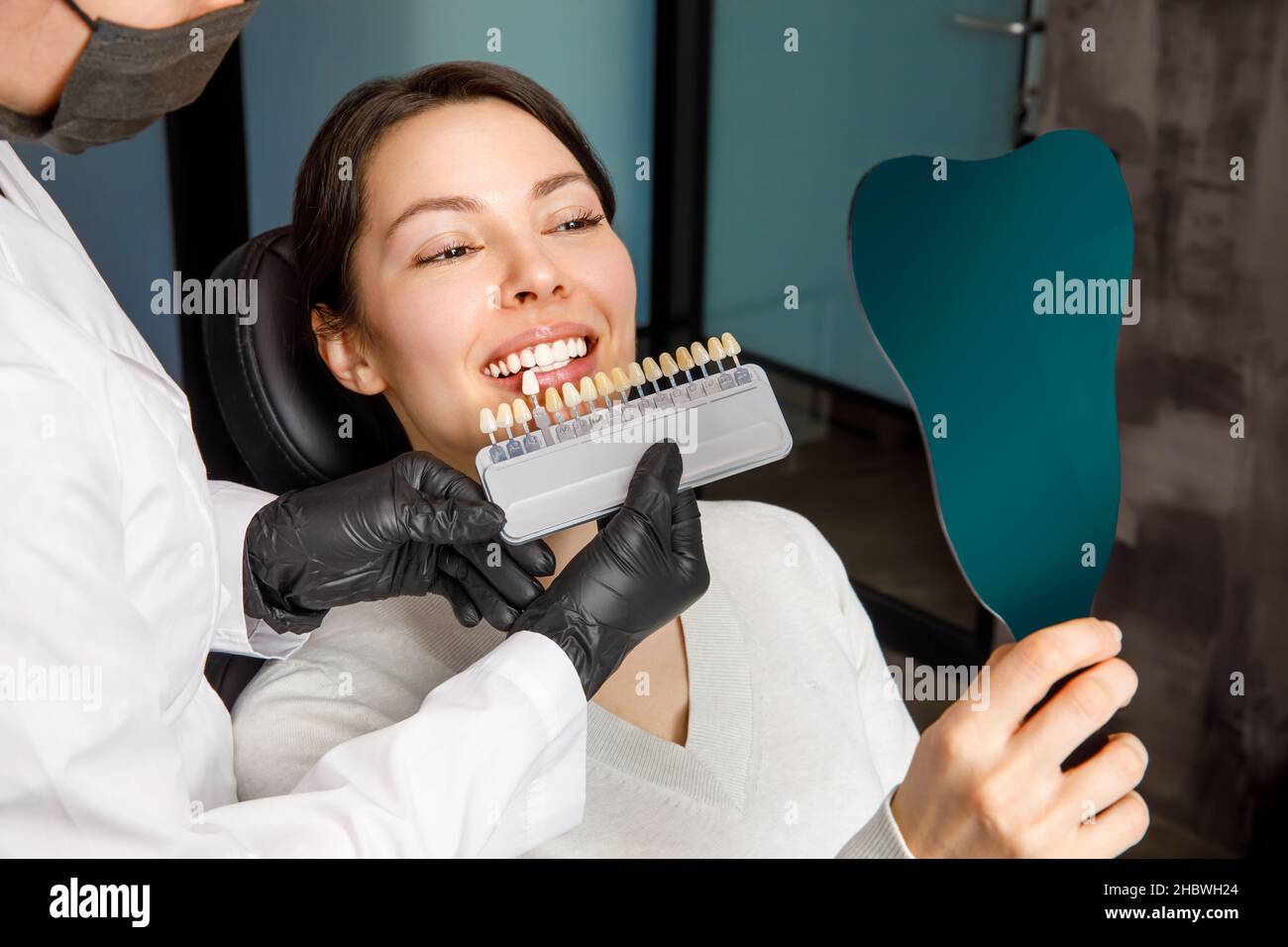 Smiling young woman. Cosmetological teeth whitening in a dental clinic. selection of the tone of the implant tooth Stock Photo
