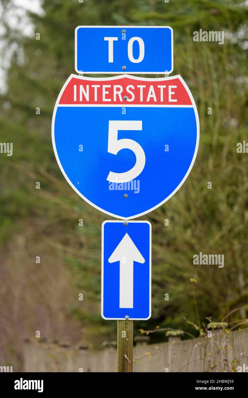 Sign indicates stright ahead to US Interstate 5 in Washington State.  The sign is red white and blue with a vertical arrow for the direction Stock Photo