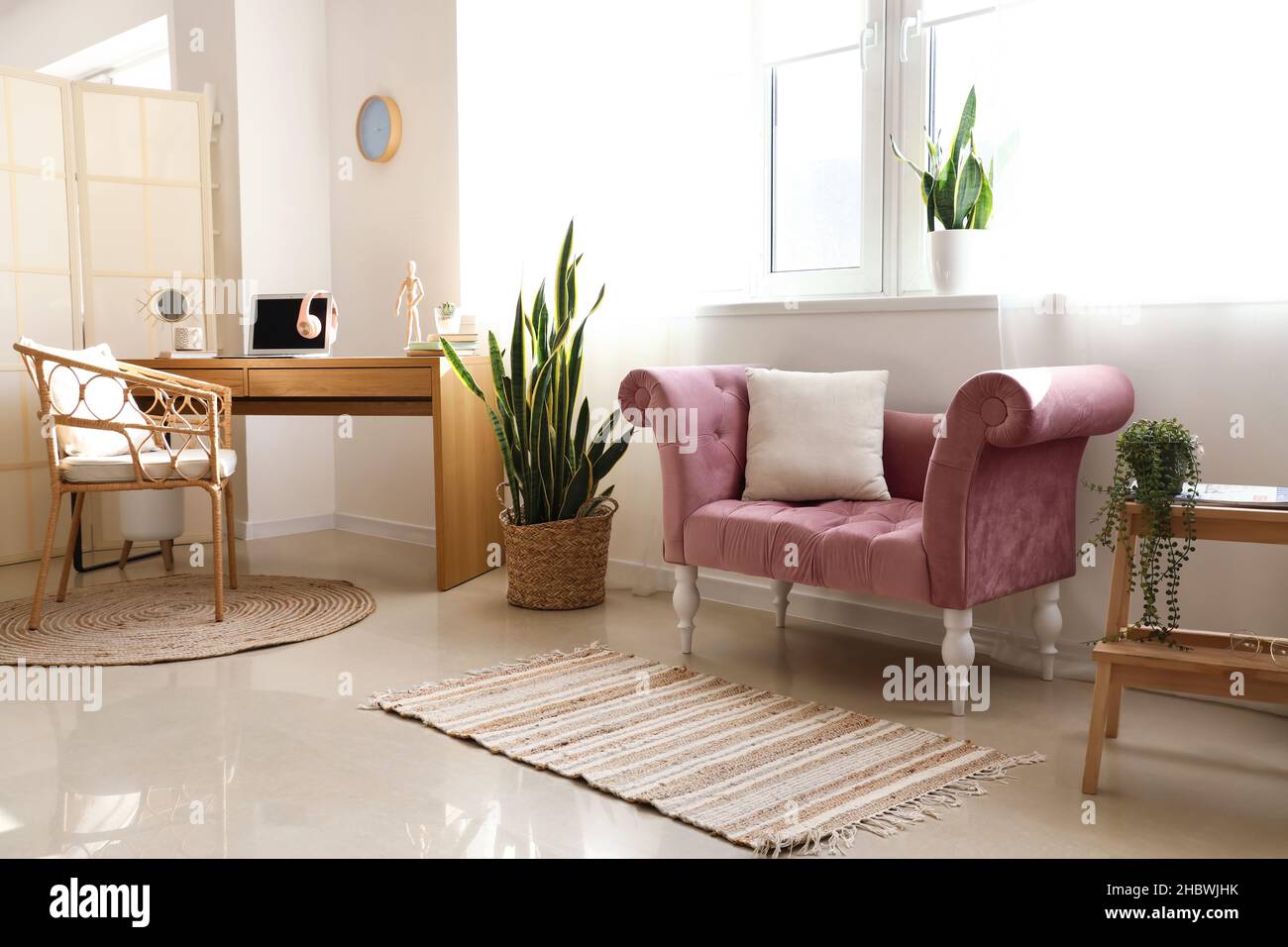 Interior of light living room with pink armchair and modern workplace