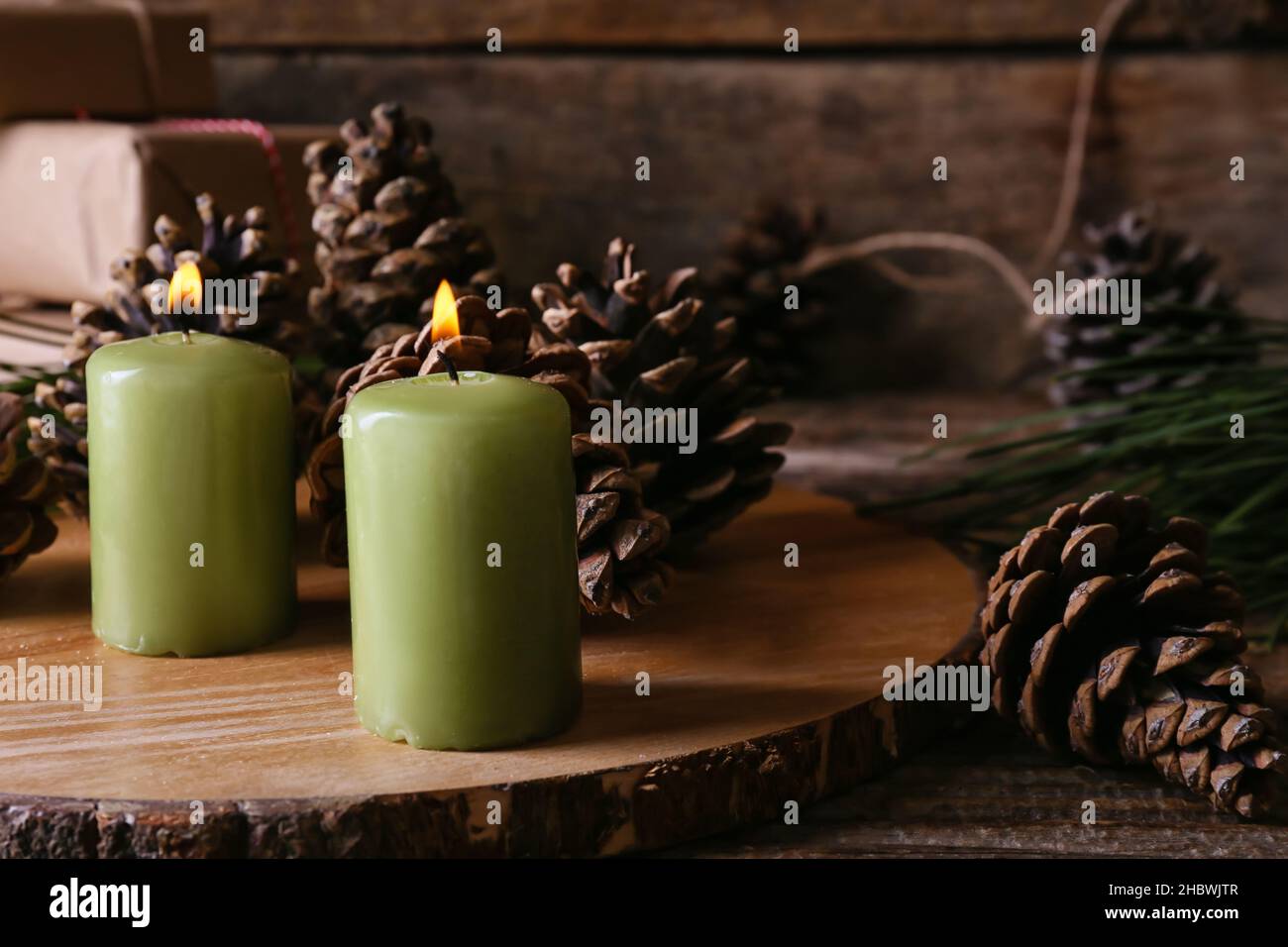 Board with burning candles and pine cones on wooden table, closeup ...